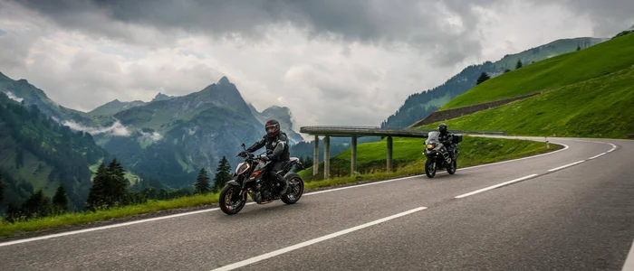 Zwei Motorräder auf bergiger Straße unter bewölktem Himmel