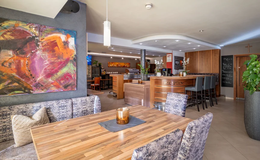 Modern restaurant area with colorful painting and wooden reception bar
