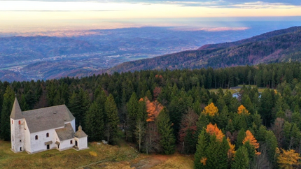 Kirche im Wald am Berg mit Aussicht auf Tal bei Sonnenuntergang