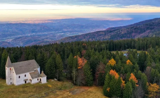 Kerk in bos op berg met uitzicht op vallei bij zonsondergang