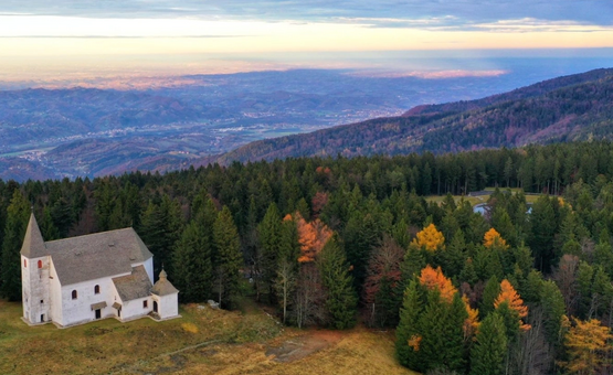 Kirche im Wald am Berg mit Aussicht auf Tal bei Sonnenuntergang