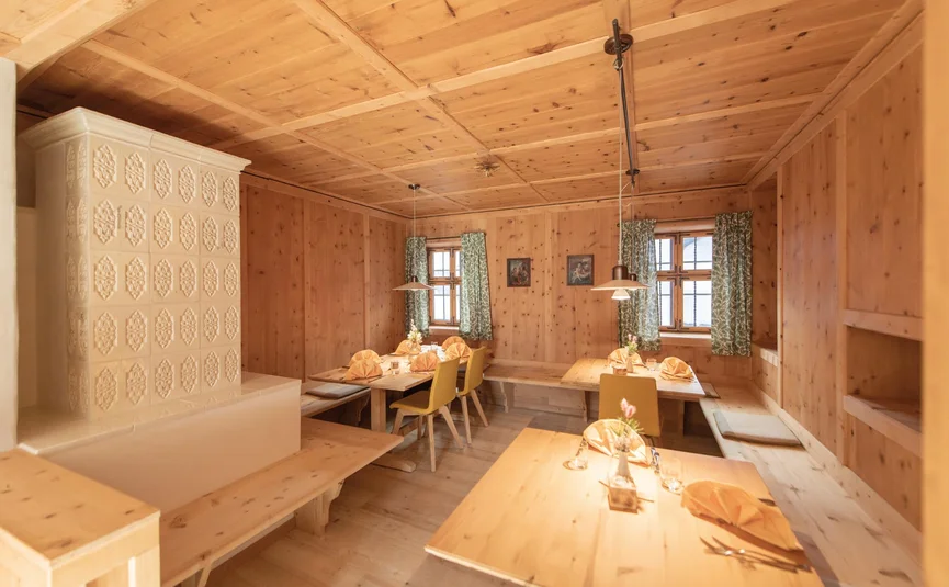 Cozy wooden dining room with tiled stove and set tables