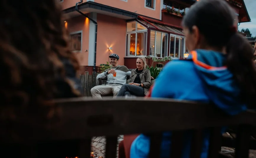Mensen zitten ’s avonds buiten voor een huis te praten