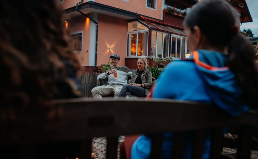 Mensen zitten ’s avonds buiten voor een huis te praten