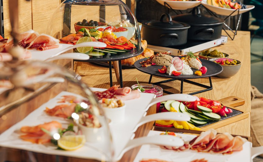 Buffet mit Aufschnitt, Frischkäse, Gemüse und Antipasti auf Holztheke
