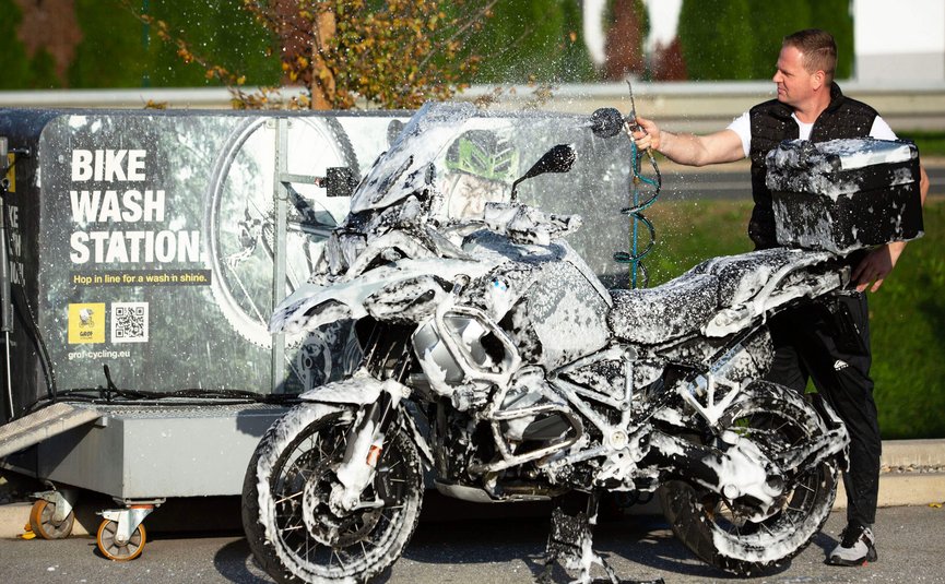 Person wäscht Motorrad an Bike Wash Station mit Schaum