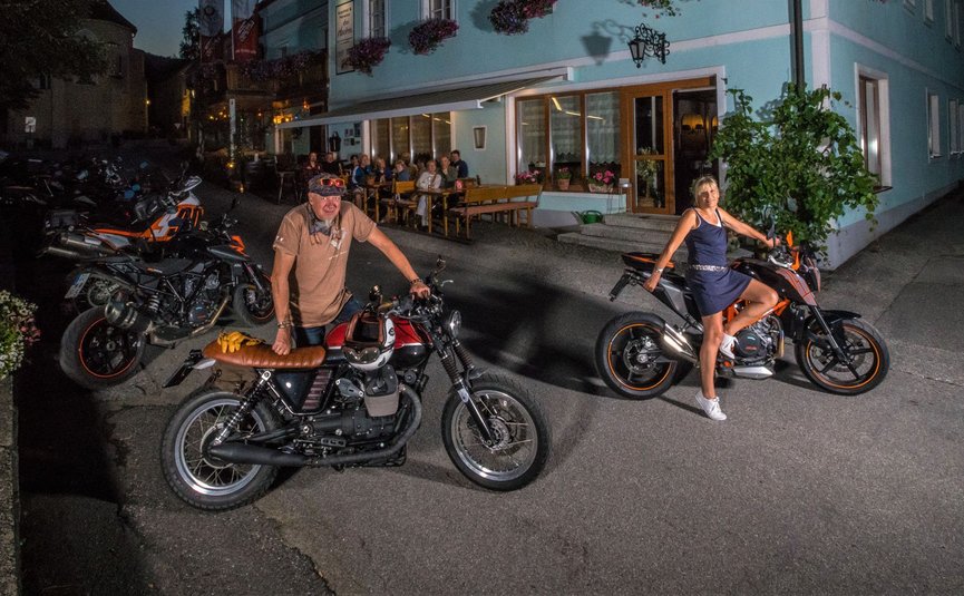 Gasthof Pension Drei Hacken *** © Moppetfoto.de Zwei Personen mit Motorrädern vor blauem Haus bei Nacht