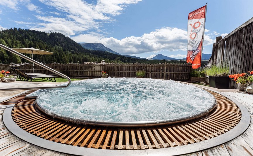 Sprudelnder Whirlpool auf Holzdeck mit Bergblick und Sonnenschirm