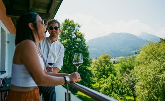 Zwei Menschen genießen Wein auf Balkon mit Bergblick