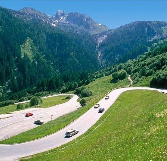 Kitzbüheler Hansi Tour (Gerlos - Zillertal - Kitzbühel) Kurvenreiche Bergstraße mit Autos vor bewaldeten Bergen und blauem Himmel