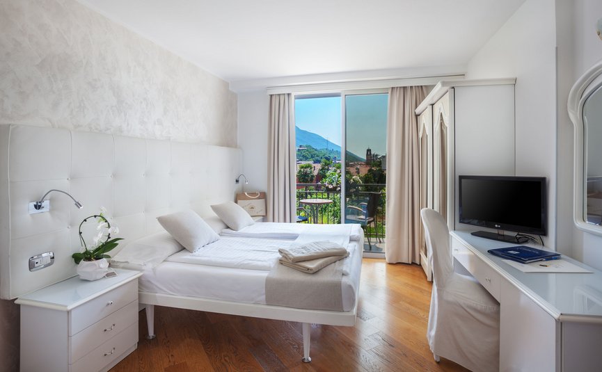 Bright hotel room with double bed, balcony, and mountain view