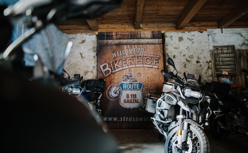 Motorräder vor einem Schild mit Willkommen im Bikerhof Route B 111 Gailtal
