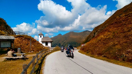 Sölkpasstour Motorradfahrer fahren auf Bergstraße neben Kapelle bei sonnigem Himmel