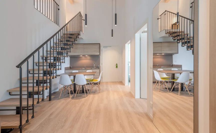 Modern living space with staircase, dining table and kitchen area