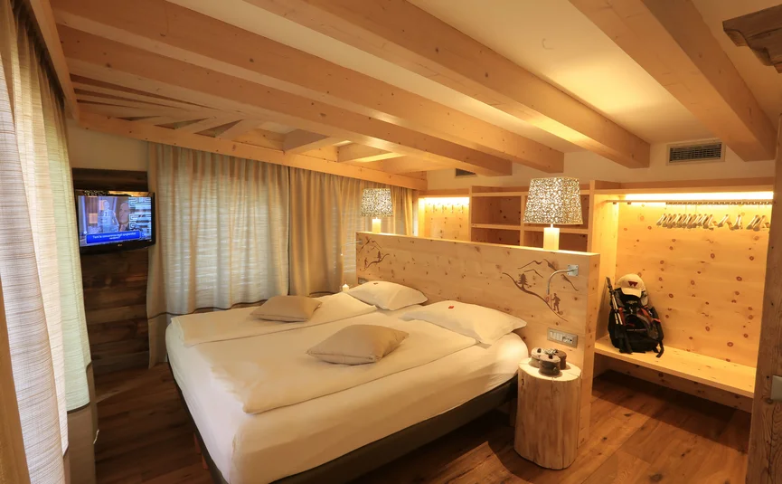 Cristallo Sport & Wellness Hotel **** © Andrea Acler Hotelzimmer mit Doppelbett, Holzbalkendecke, Vorhängen und Fernseher