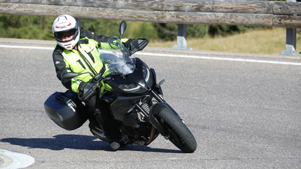 Motorradfahrer in Schutzkleidung fährt auf kurviger Straße
