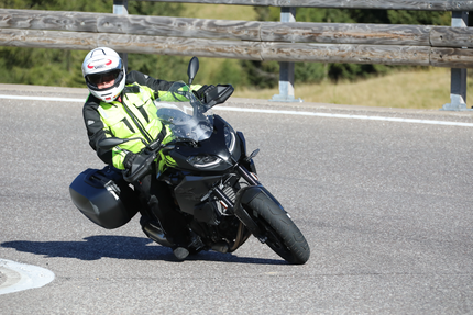 Motorradfahrer in Schutzkleidung fährt auf kurviger Straße