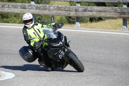 Motorcyclist wearing safety gear riding on a curved road