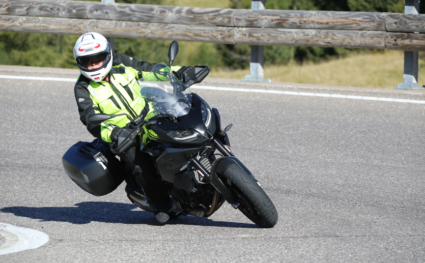 Motorradfahrer in Schutzkleidung fährt auf kurviger Straße