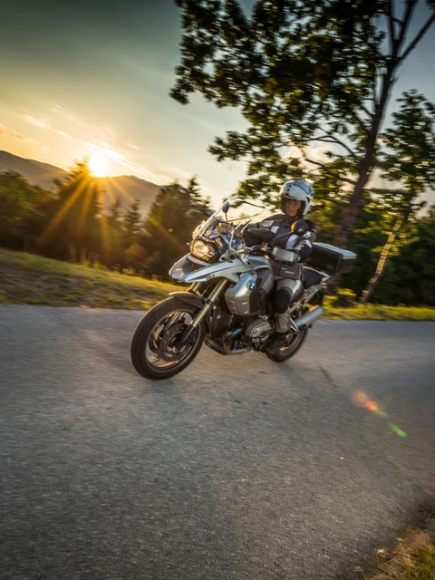 Motorcyclist riding on winding road at sunset in rural area