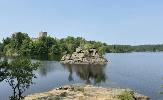 Rocky island in lake with forest shore and an old castle in the background