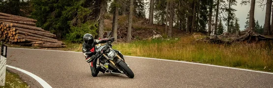 Motorradurlaub in Valsugana – Kaiserjägerstraße © Andrea Acler Motorradfahrer fährt kurvig durch bewaldete Straße bei bedecktem Himmel