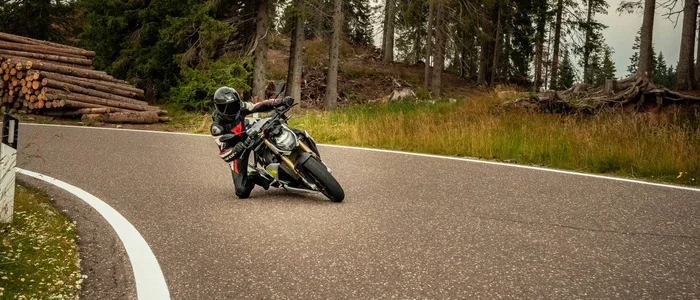 Valsugana - Kaiserjägerstrasse © Andrea Acler Motorcoureur die bocht neemt op bosrijke weg bij bewolkte lucht