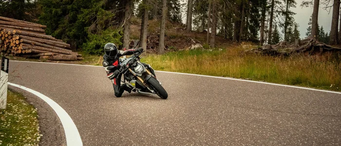 Valsugana – Kaiserjägerstraße © Andrea Acler Motorradfahrer fährt kurvig durch bewaldete Straße bei bedecktem Himmel
