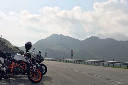 Motorcycles parked on mountain road with mountains in background