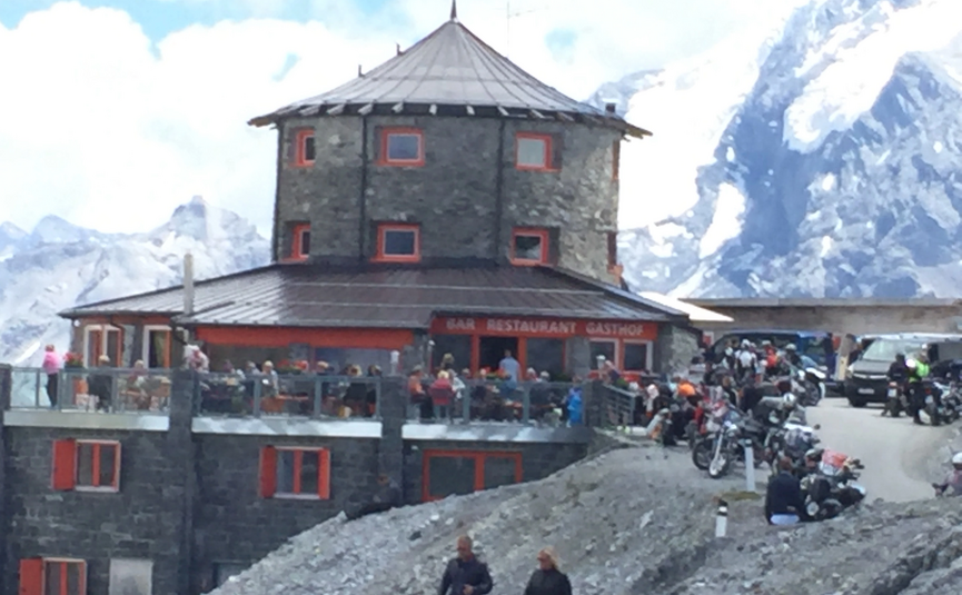 MoHo Schönauer Hof Tour Stelvio Variant 3 Livigno Round stone building with restaurant in mountains and motorcycles