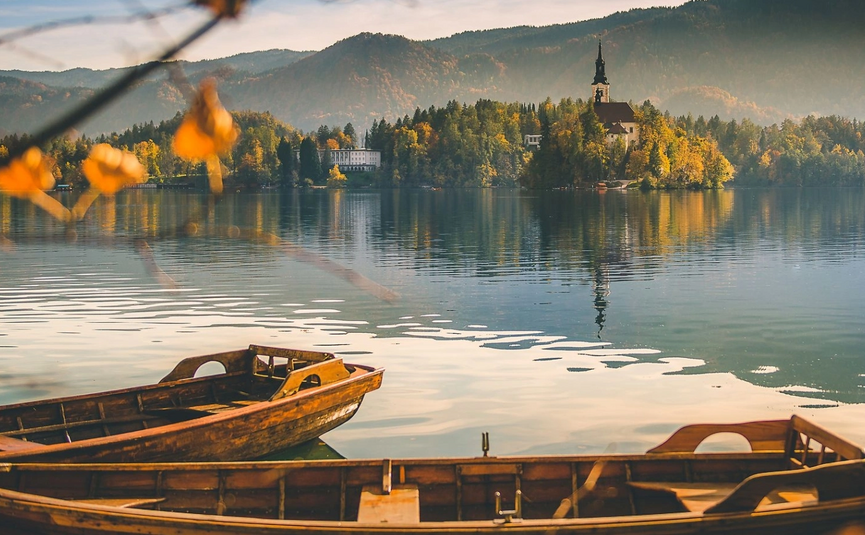 Booten op meer met eilandkerk en herfstbomen