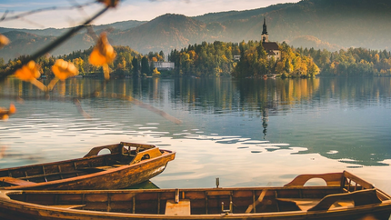 Booten op meer met eilandkerk en herfstbomen