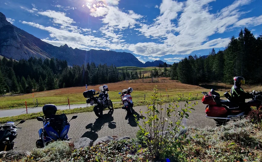 Motorcycles parked on sunny day with mountains and blue sky in background