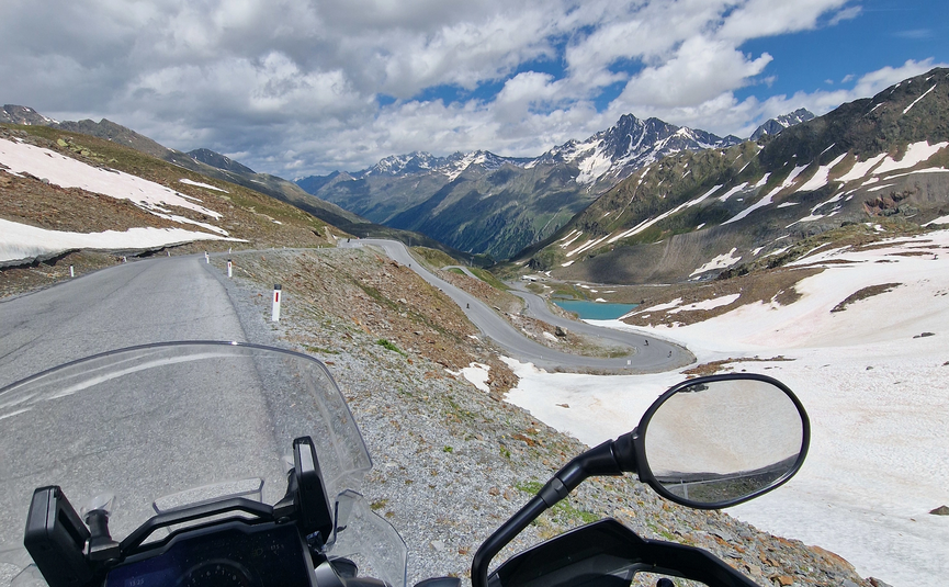 MoHo Schönauer Hof tour 13 Smugglers' tour Samnaun View from motorcycle on winding mountain road with snow and mountains