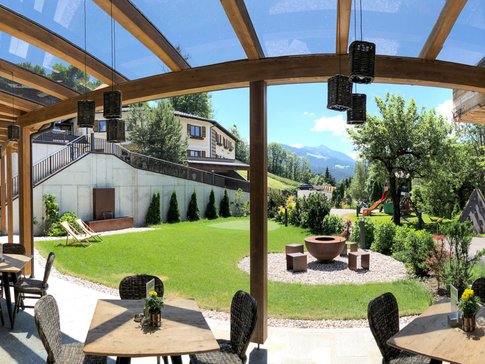 Overdekt terras met tafels, stoelen en uitzicht op bergen in een tuin