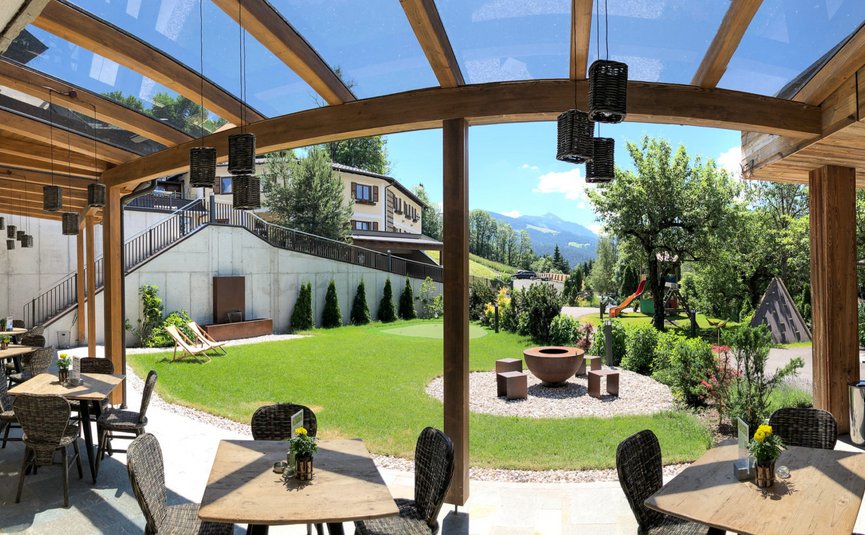 Landhotel & Gasthof Laudersbach *** © Manuel Jäger Überdachte Terrasse mit Tischen, Stühlen und Bergblick in einem Garten