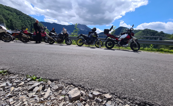 Steirische Satteltour Motorradfahrer mit Motorrädern auf Bergstraße unter bewölktem Himmel