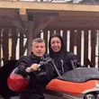 Ingrid & Luca Vanzo © Hotel La Stüa Mann und Frau auf orangem Motorrad unter Holzdach