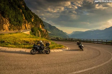 16. Fleimstalrunde - Manghen - Valles www.ludwigshof.it Motorradfahrer auf kurvenreicher Bergstraße bei Sonnenuntergang