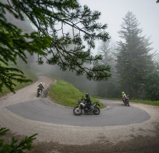 Motorcyclists riding on a winding mountain road in foggy weather