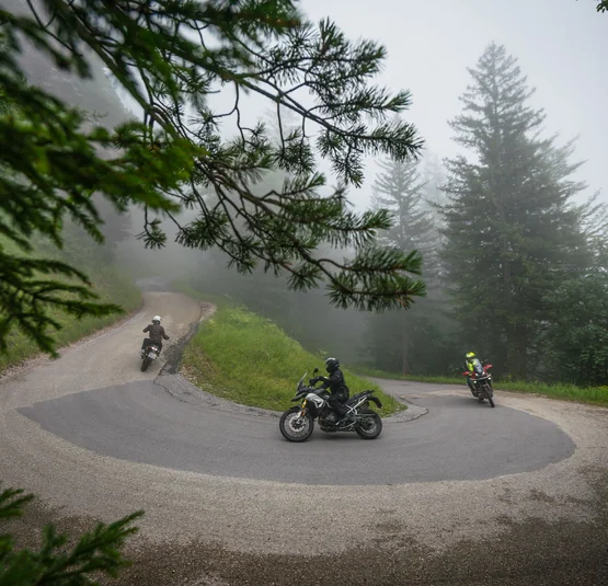 Motorrijders op kronkelende bergweg bij mistig weer