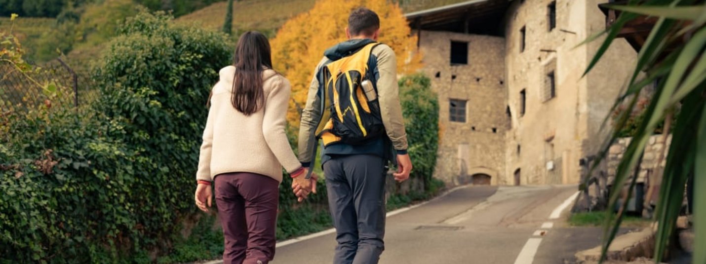 Herbstliche Relax- & Feinschmeckertage Paar geht Hand in Hand eine Straße in ländlicher Umgebung entlang