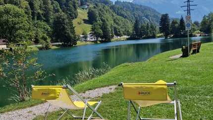 Zwei gelbe Stühle am See mit Bergblick unter blauer Himmel
