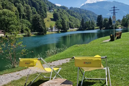 Two yellow chairs by a lake with mountain view under blue sky