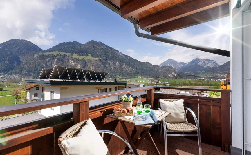 Balcony with chairs, table, and mountain view on a sunny day