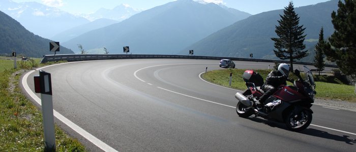 Hotel am Reschensee *** © The Dilitz Company GmbH Motorradfahrer auf kurviger Bergstraße mit Bergen im Hintergrund