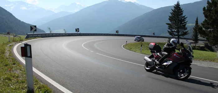 Motorcyclist riding on a winding mountain road with mountains in the background