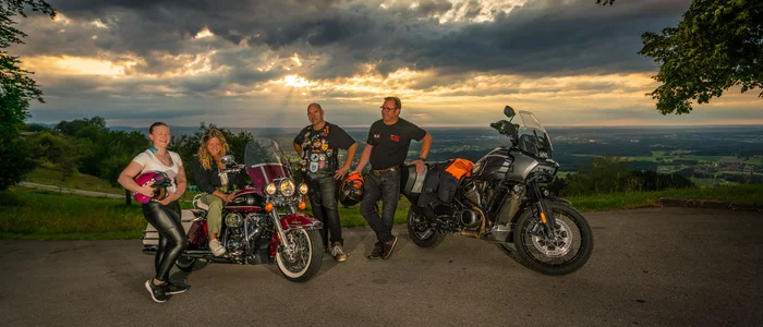 Four motorcyclists with two motorcycles at sunset on a viewpoint