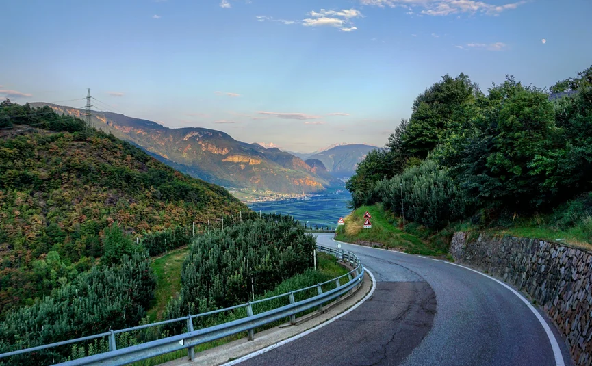 Dolomiten - Kriegerrunde Kurvige Bergstraße mit grünen Bäumen und Bergen im Hintergrund