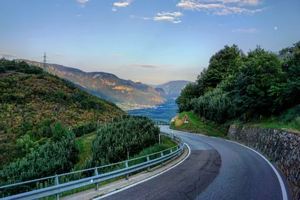 Curvy mountain road with green trees and mountains in the distance